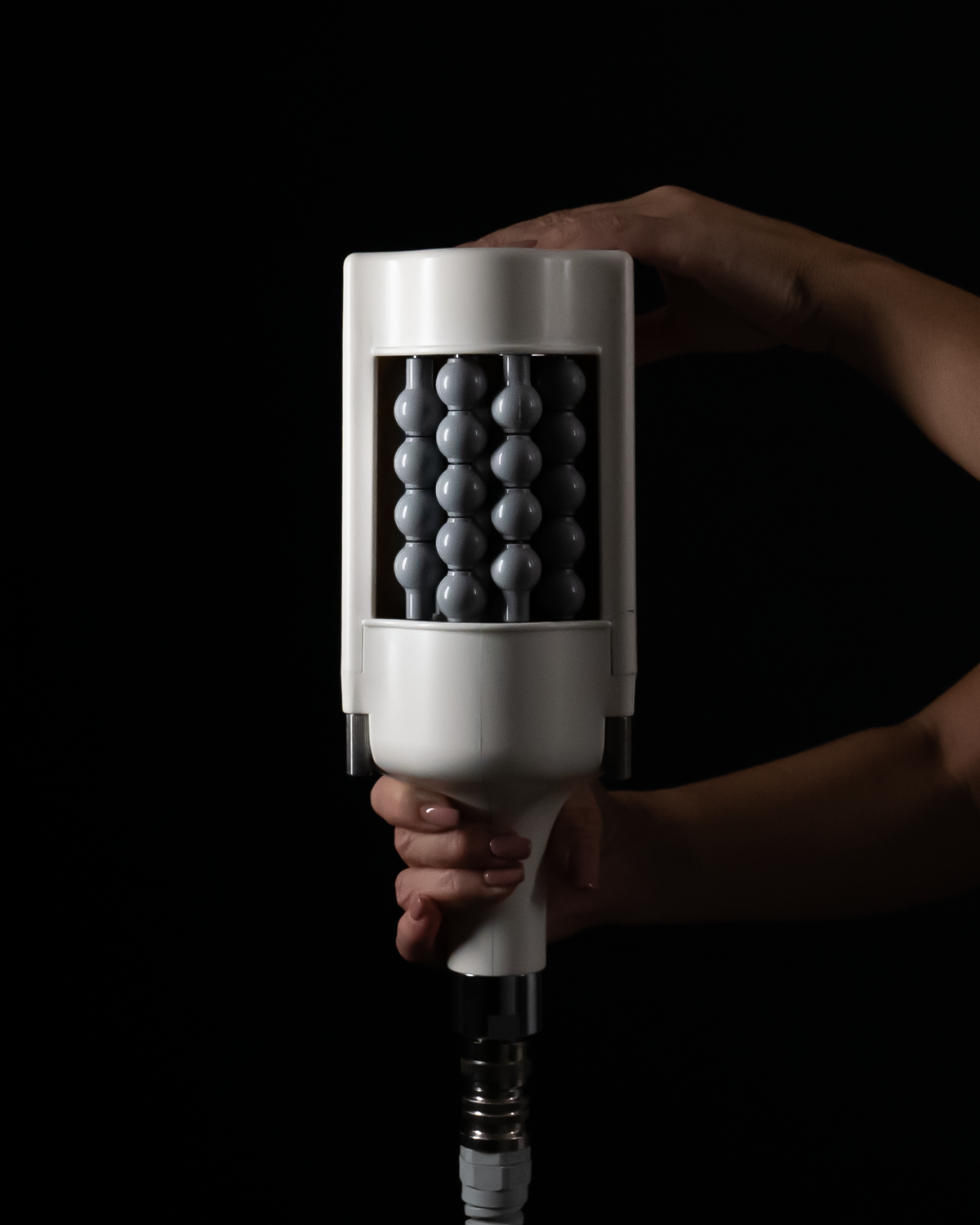 Hand holding a massage device with gray balls.