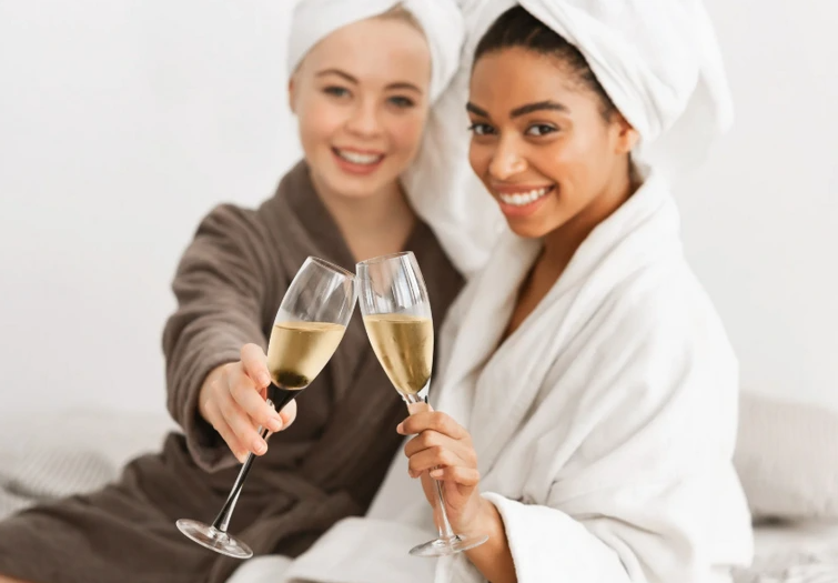 Friends enjoying champagne in cozy robes.