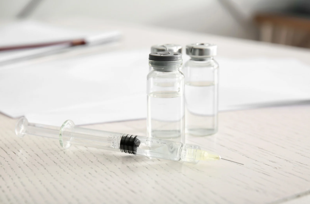 Syringe and vials on a white table.