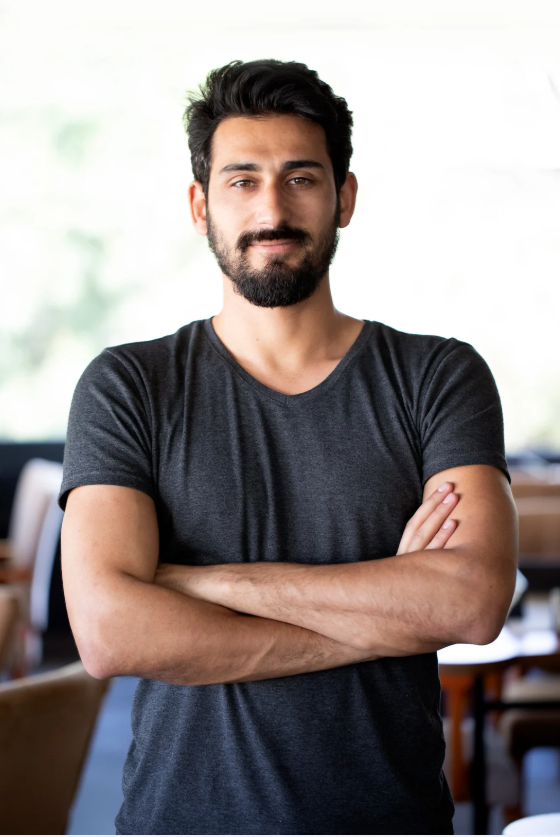 Man with beard posing confidently indoors.