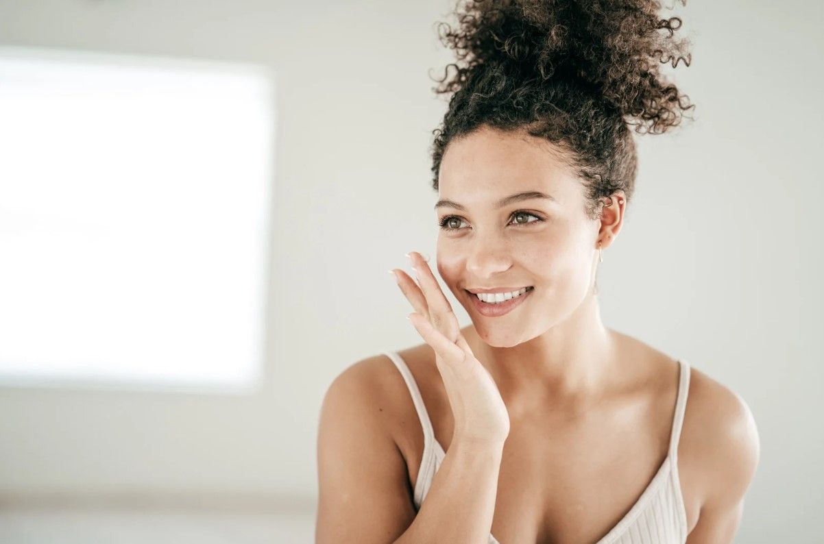 Woman with curly hair, natural makeup, thoughtful expression.