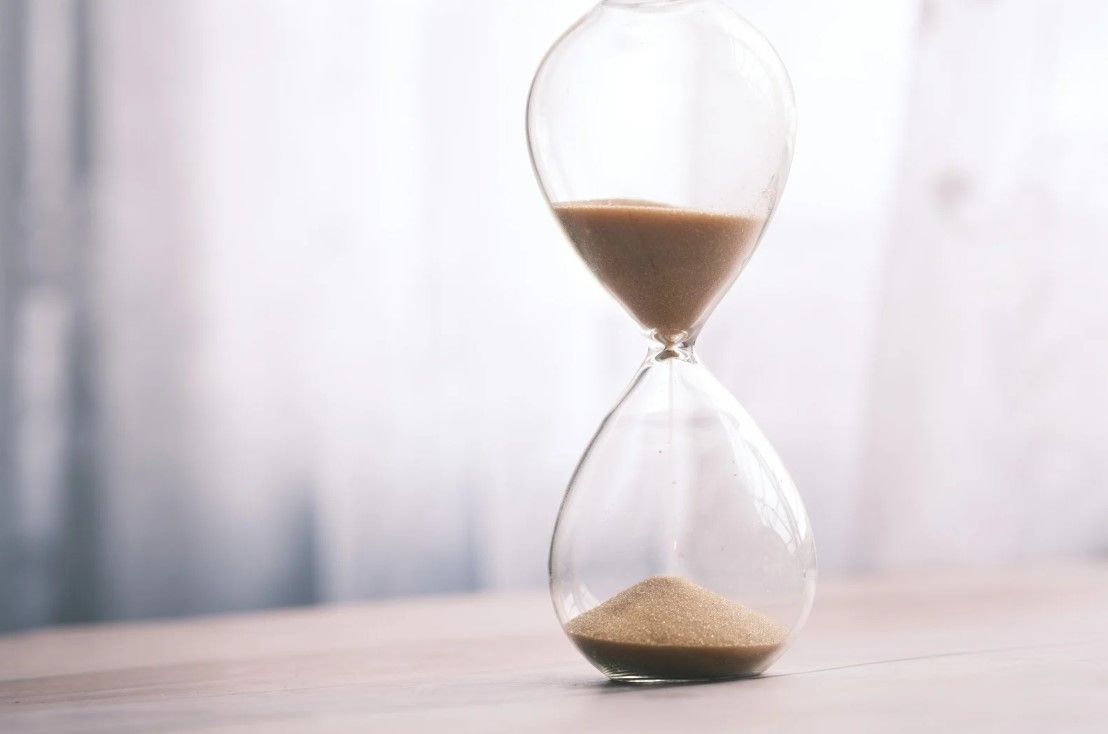 Hourglass on a wooden table with sand.