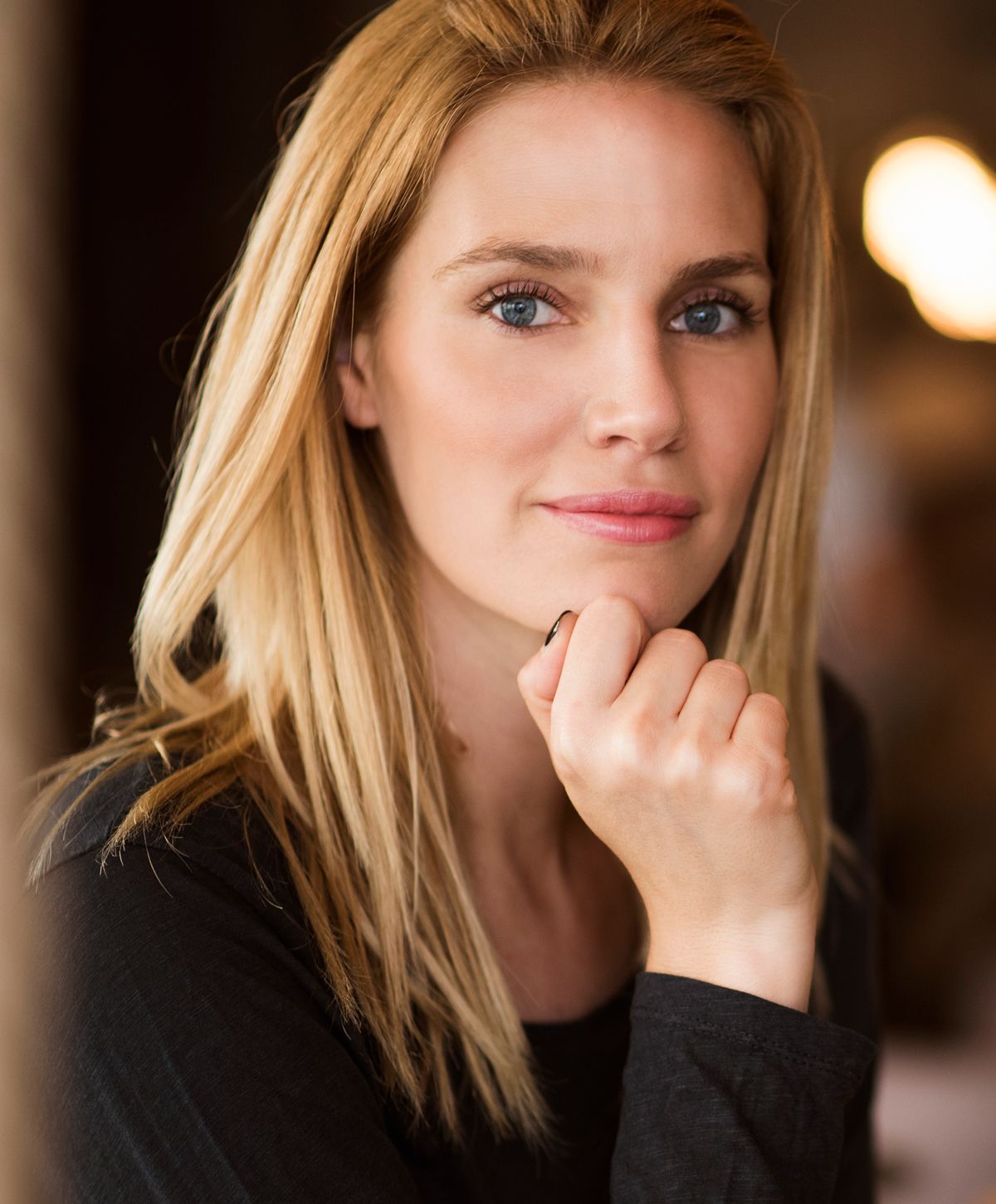 Woman with blonde hair resting her chin.