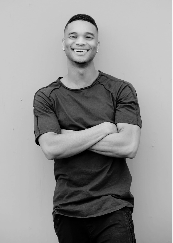 Smiling person with crossed arms against wall.