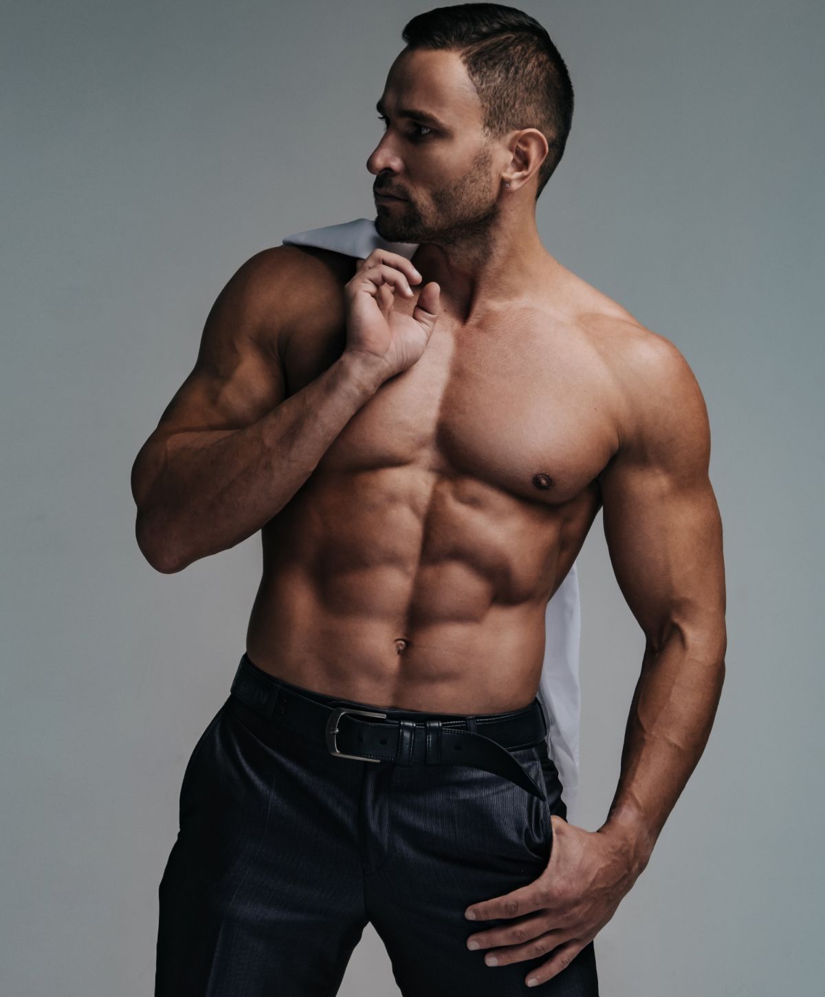 Muscular man posing with a suit jacket.