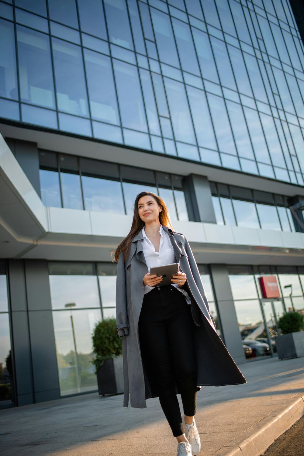 Woman in coat walking outside modern building.
