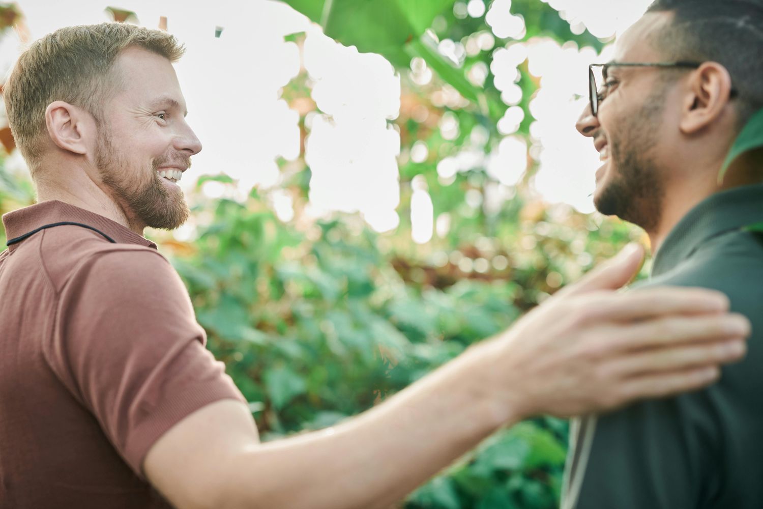 Two friends smiling in a green environment.
