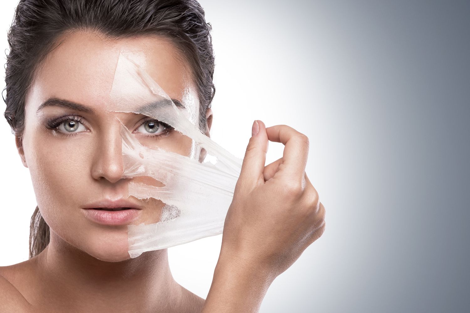 Woman removing facial mask for skincare treatment.